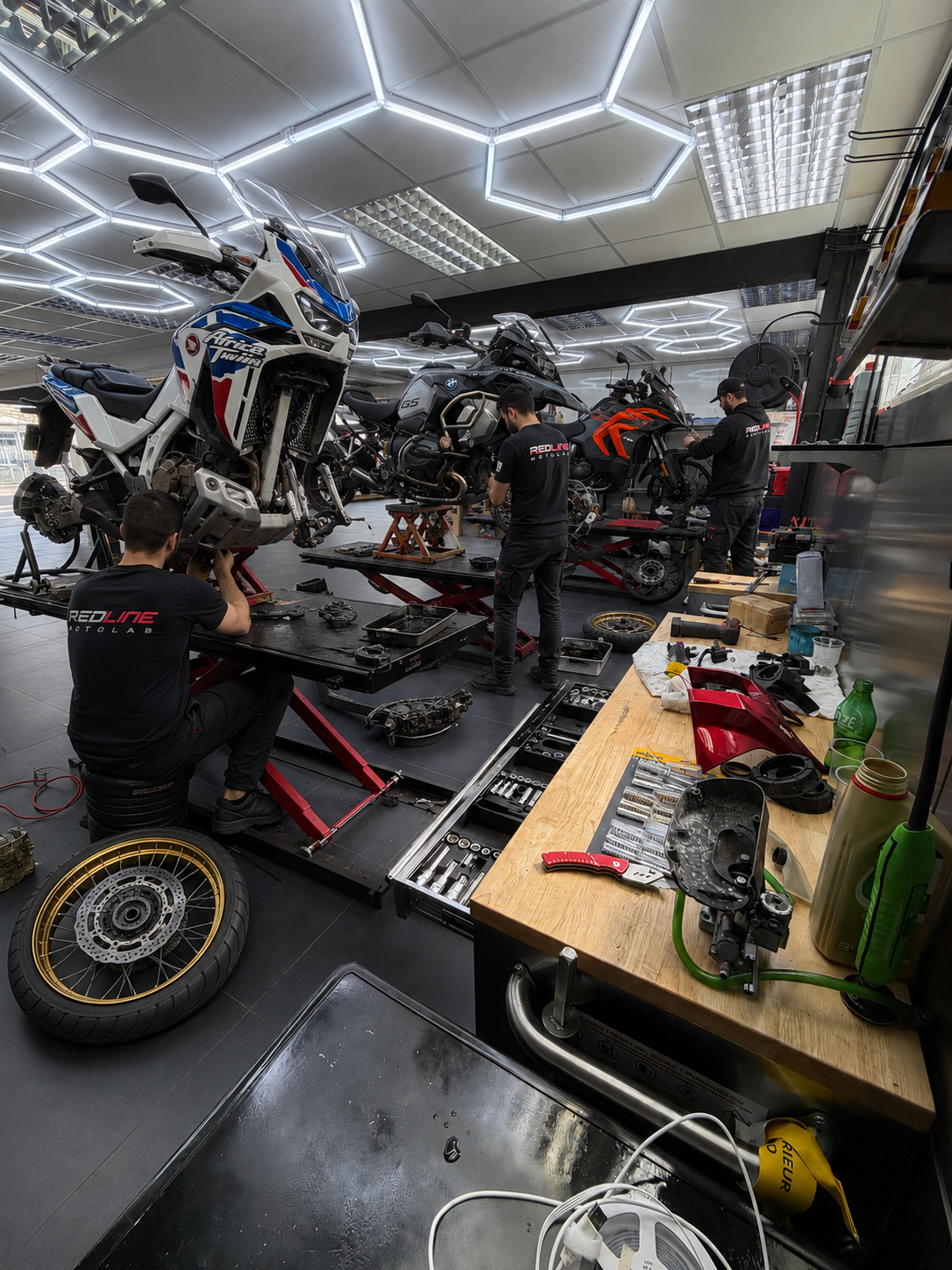 Adventure motorcycles on lifts for tyre fitting at Redline MotoLab, Croydon