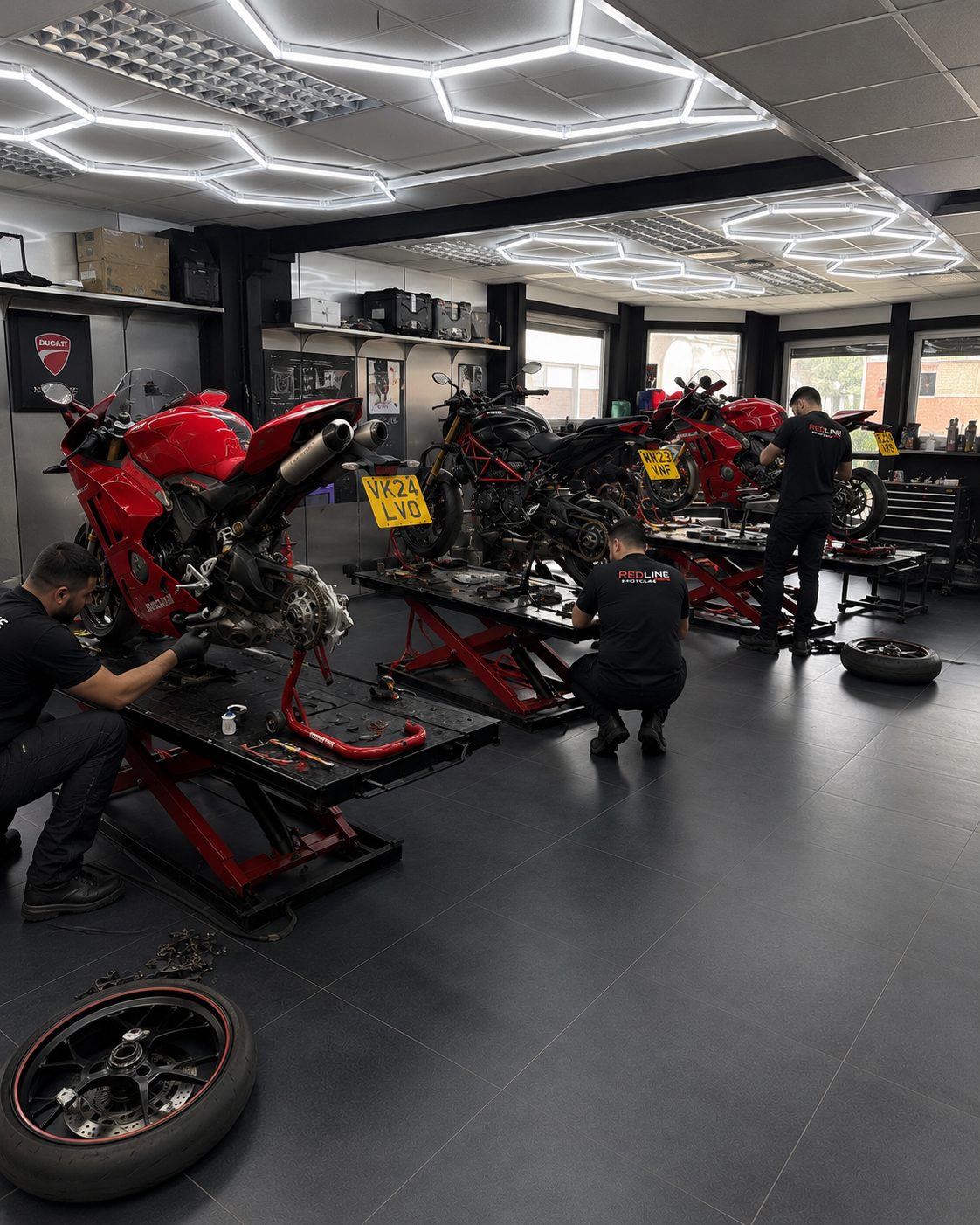 Motorcycles on lifts being serviced inside the Redline MotoLab workshop in Croydon